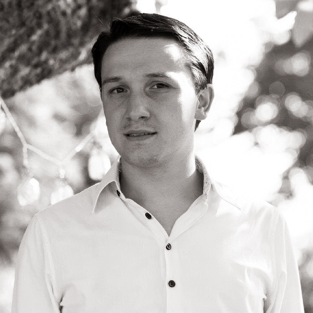 Porträt eines Mannes in weißem Hemd vor einem Baum.