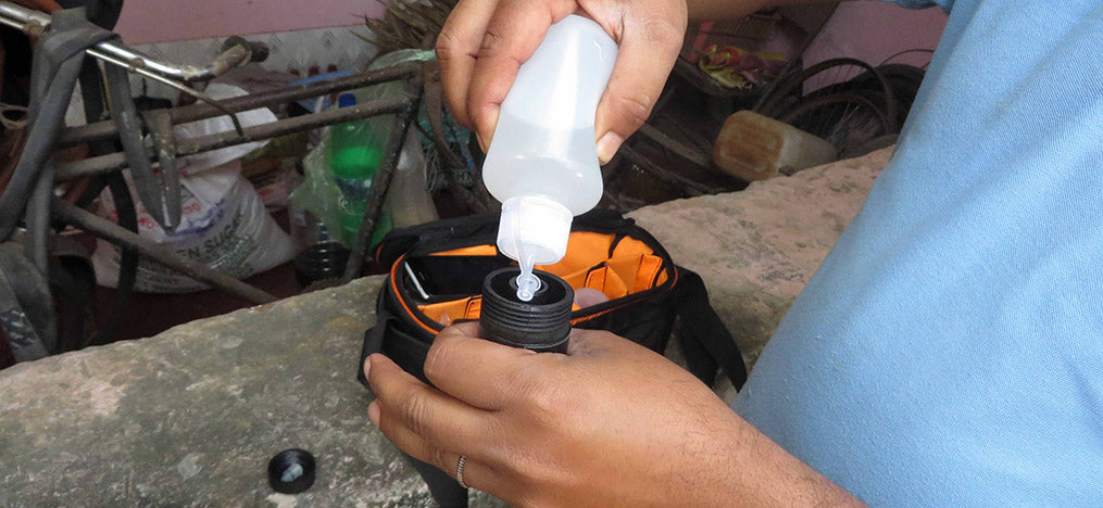 Eine Person gießt Flüssigkeit aus einer kleinen Flasche in eine andere.